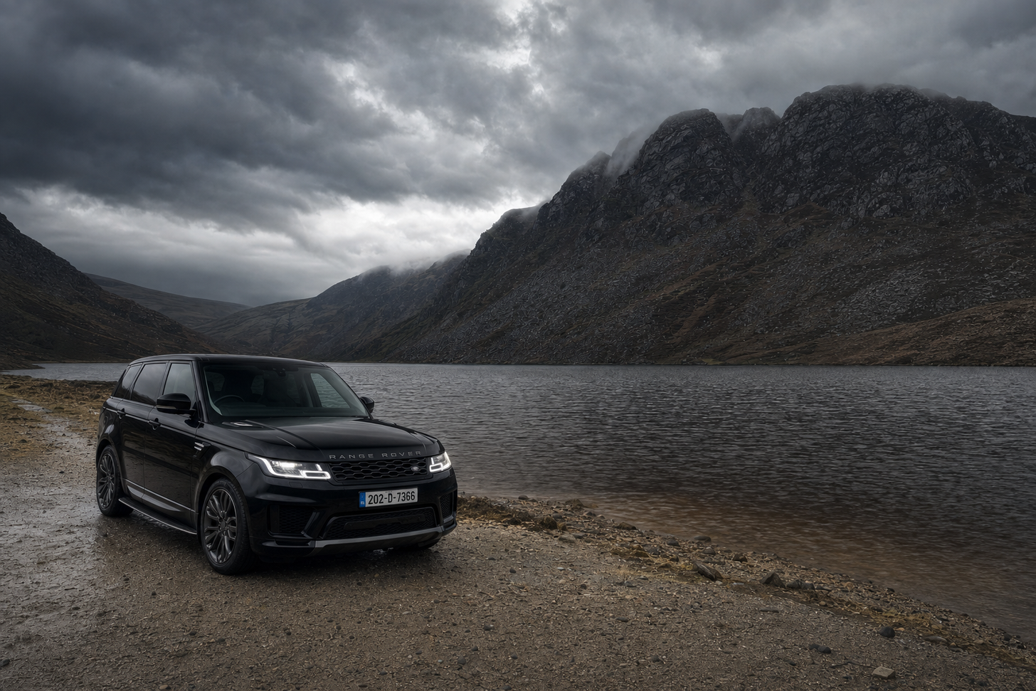 Black Range Rover beside a mountain lake in heavy New Zealand rain.